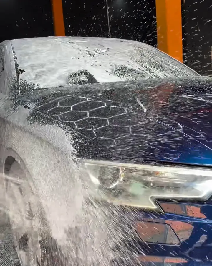Audi azul coberto de espuma durante a pré-lavagem no box