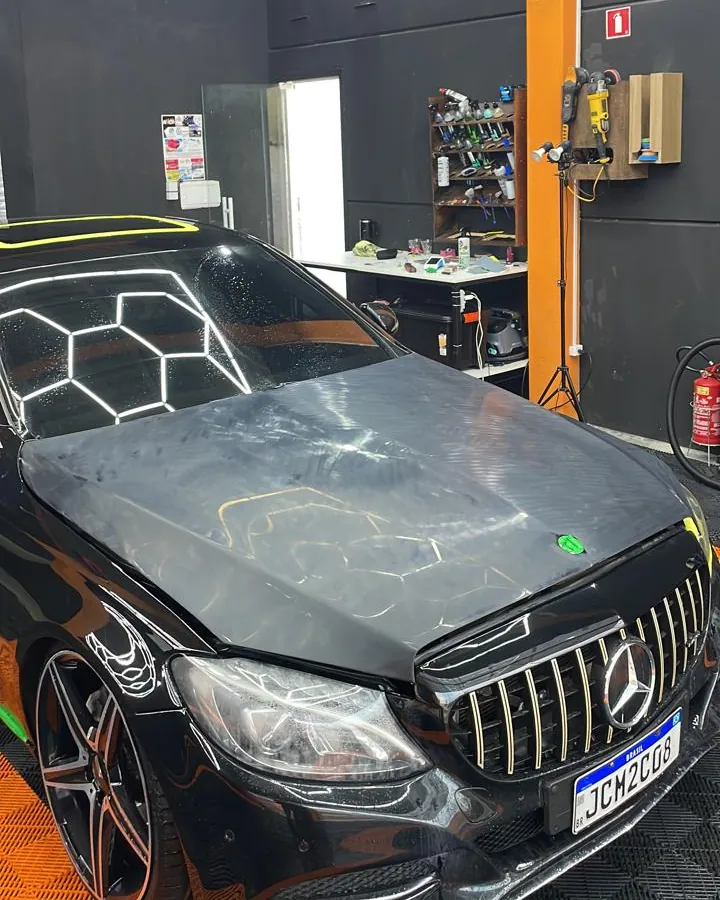 Capô de Mercedes-Benz com composto de polimento aplicado e ferramentas ao fundo